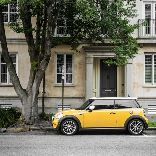 An image of a yellow mini coupe parked on an european street.